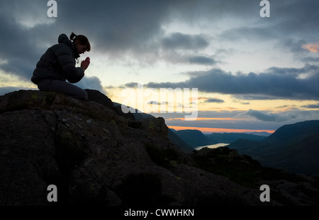 Una donna in preghiera a Dio sulla cima di una montagna. Foto Stock