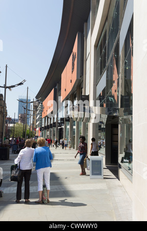 Due donne pausa al di fuori dell'Harvey Nichols nel mezzo dello shopping sulla nuova Cattedrale Street a Manchester. Foto Stock