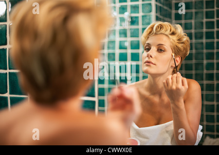 Donna di applicare il trucco in bagno Foto Stock