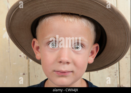 Ragazzino con il cappello da cowboy contro una vecchia porta di legno Foto Stock