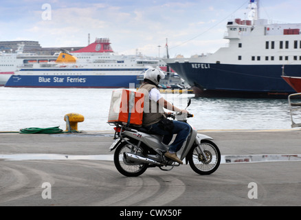 Una moto uomo di consegna sulla banchina del porto del Pireo ad Atene in Grecia Foto Stock