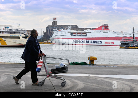 Un uomo spingendo un carrello della spesa sul dock al porto del Pireo ad Atene in Grecia Foto Stock