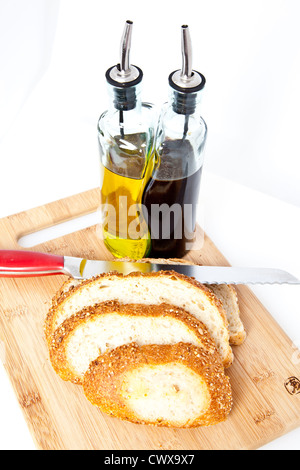 Fette di pane su un tagliere con coltello e olio e aceto. Foto Stock