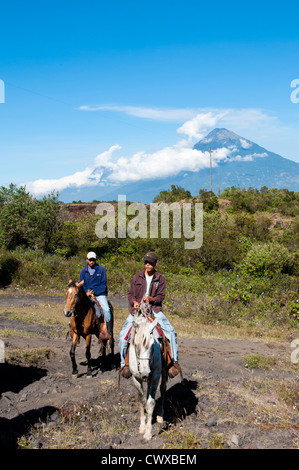 Equitazione sul vulcano Pacaya, con Fuego vulcano a distanza Antigua, Guatemala, America centrale. Foto Stock