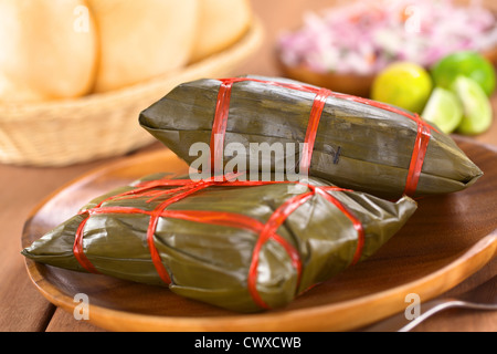 Peruviano tamales avvolti in foglie di banano, in cui essi sono cotti, all'interno è un mais a base di pasta con carne Foto Stock