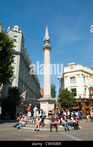 Il Sundial pilastro con gente seduta al di sotto a Seven Dials a Covent Garden dove 7 strade convergono Foto Stock