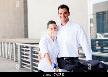 Felice coppia giovane spingendo carrello bagagli in aeroporto Foto Stock