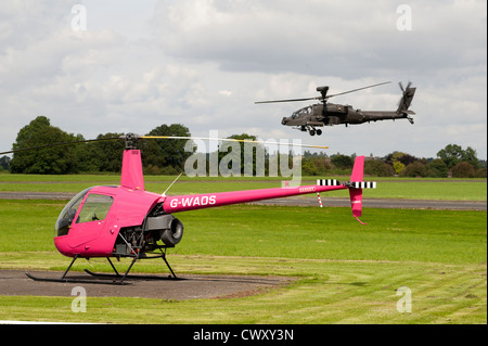 Piccoli e grandi - Robinson R22 beta e RAF Apache elicotteri da attacco condividono Wolverhampton Aeroporto. SCO 8373 Foto Stock