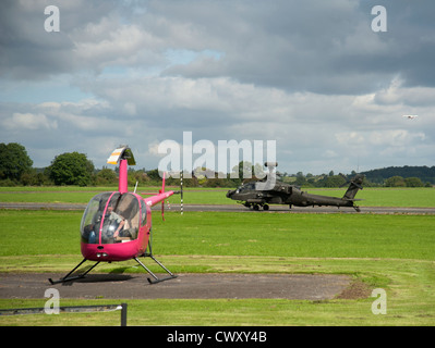 Piccoli e grandi - Robinson R22 beta e RAF Apache elicotteri da attacco condividono Wolverhampton Aeroporto. SCO 8376 Foto Stock