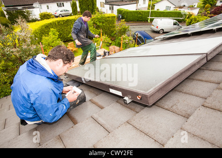 Il fissaggio di un solare pannello termico per il riscaldamento di acqua in una casa tetto in Ambleside, Regno Unito. Foto Stock