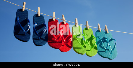Multi-flipflops colorati su un stendibiancheria con un cielo sfondo blu Foto Stock