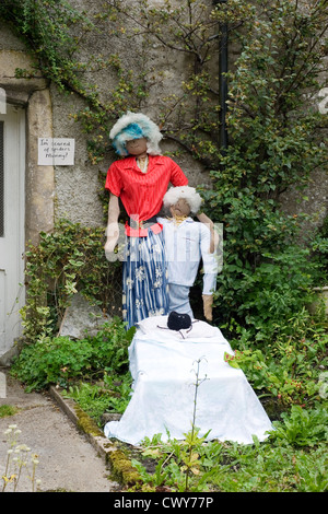 Scarecrows a kettlewell festival raffigurante un uomo e una donna in piedi dalla porta del cottage Foto Stock