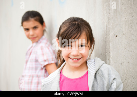 Sorridente ragazza appoggiata contro la parete di cemento Foto Stock