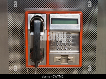 Orange telefono pubblico su sfondo metallico Foto Stock