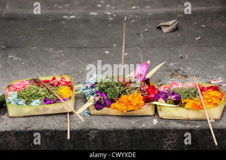 Offerte di religiose di fiori e cibo lasciato sui gradini di un tempio indù di Legian, meridionale di Bali, Indonesia Foto Stock