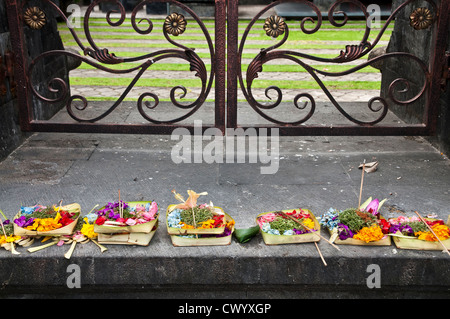 Offerte di religiose di fiori e cibo lasciato sui gradini di un tempio indù di Legian, meridionale di Bali, Indonesia Foto Stock