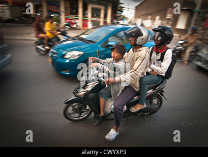 Famiglia di 3 su un ciclomotore in Legian la strada principale di Legian, meridionale di Bali, Indonesia. Foto Stock