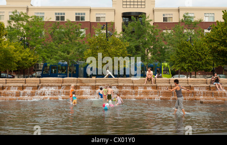 Abitanti delle città rinfrescarvi nel parco urbano fontana e piscina come un tram che va da Foto Stock