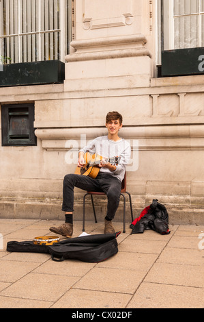 Un giovane musicista di strada con la sua chitarra a Norwich, Norfolk , Inghilterra , Inghilterra , Regno Unito Foto Stock