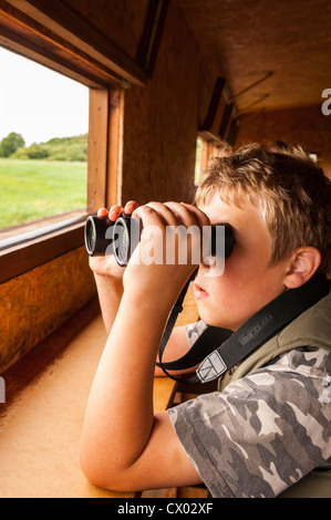 Un 8 anno vecchio ragazzo birdwatching in un nascondere all'Minsmere RSPB bird reserve nel Suffolk , Inghilterra , Inghilterra , Regno Unito Foto Stock