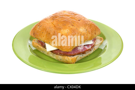 Un fresco e capicolla panino al formaggio, con semi di papavero e cipolla pane quadrato su una piastra verde. Foto Stock