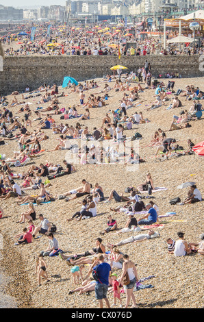 Le persone accorrono per la spiaggia per godere del sole e delle temperature elevate sulla Spiaggia di Brighton. Foto Stock