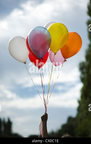 Persona in possesso di multi colore palloncini elio Foto Stock