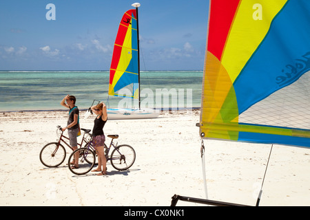 I ciclisti sulla spiaggia tra gli Hobie cat catamarani, Bjewuu, Zanzibar Africa Foto Stock