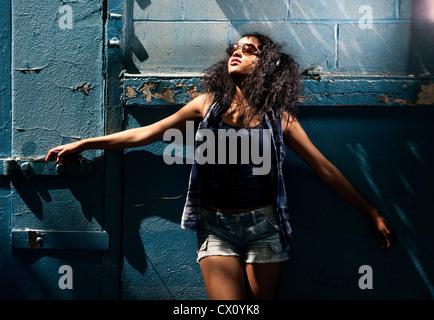 Giovane donna che indossa gli occhiali da sole nel contesto urbano Foto Stock