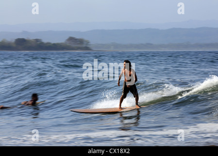 Locale longboard giavanese surfer surf un ondata di Batu Karas, West Java, Indonesia. Foto Stock