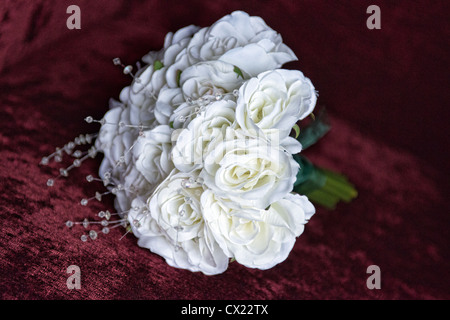 Un posie di rose bianche su un velluto rosso sfondo Foto Stock