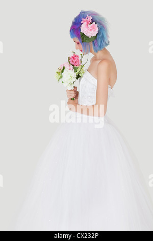 Vista laterale della giovane donna in abito da sposa con capelli tinti contro uno sfondo grigio Foto Stock