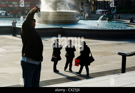 I turisti e gli artisti interpreti o esecutori, Trafalgar Square fontana, London, England, Regno Unito Foto Stock