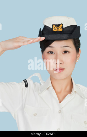 Ritratto di una giovane e bella US Navy officer salutando su fondo azzurro Foto Stock