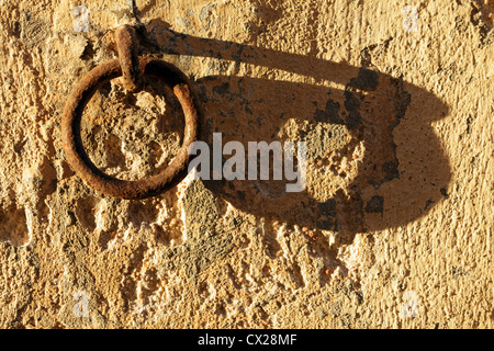 Vecchio arrugginito anello di ormeggio sul muro di pietra al tramonto con ombre lunghe Foto Stock