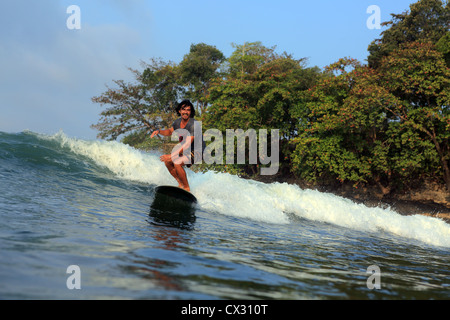 Surfista locale surf la rottura del punto onda su un longboard a Batu Karas nel West Java. Foto Stock