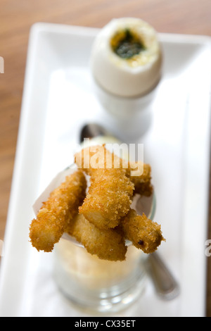 Frutti di mare goujons in breadcrumb rivestimento sul piatto bianco con uovo sodo Foto Stock