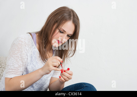 Bella giovane donna l'applicazione di vernice per unghie Foto Stock