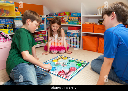 Tre fratelli sono nella loro sala giochi la riproduzione di un gioco di bordo. Foto Stock