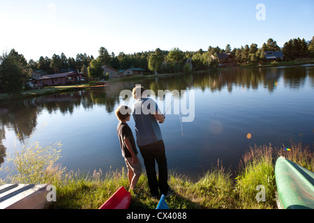 Fratello, età di undici anni, insegnamento fratello minore come utilizzare una canna da pesca in un lago in Colorado, Stati Uniti d'America. Foto Stock