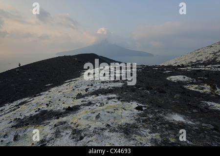 Il pendio coperto di zolfo ricco flusso in corrispondenza di Anak Krakatau con l'isola di Rakata in background; Sunda Strait, Indonesia. Foto Stock