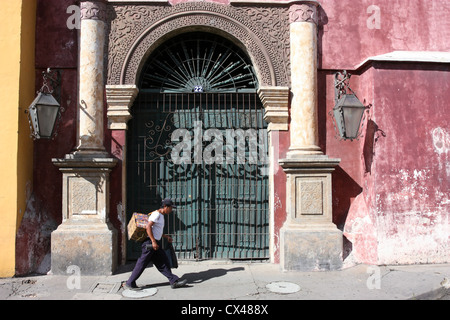 Local man walking passato porta ornati in La [UNESCO World Heritage Site] di Antigua Guatemala America Centrale Foto Stock