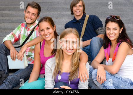 Gli studenti seduti sulle scale di scuola sorridente teens college campus amici Foto Stock