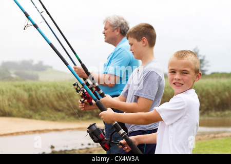 Due giovani nipoti la pesca con il loro nonno in riva al lago Foto Stock