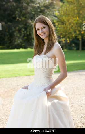 Giovane donna in crema senza spalline abito nuziale holding gonne in motivi di Sede statali Foto Stock