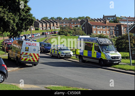 Auto della Polizia e furgoni parcheggiati su un alloggiamento estate in Brighton mentre la polizia effettuare una droga raid Foto Stock