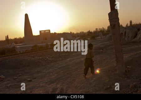 Un giovane ragazzo di Uighur passeggiate lungo una via in Turpan, Xinjiang, Cina Foto Stock