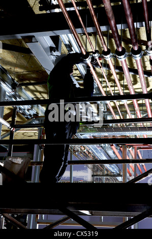 Workman fissaggio di tubazioni sulla sommità del ponteggio Foto Stock