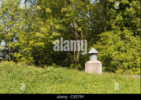 Albero di ventilazione camino per un sotterraneo al di sotto del suolo abitazione contrasta con prato circostante di pascoli e boschi Foto Stock