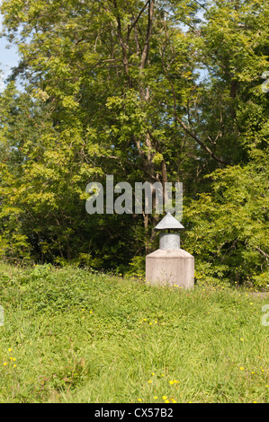 Albero di ventilazione camino per un sotterraneo al di sotto del suolo abitazione contrasta con prato circostante di pascoli e boschi Foto Stock